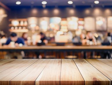 Empty wooden table with a blurred cafe background.