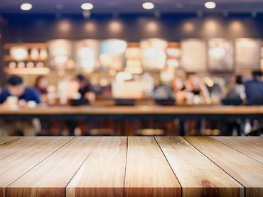 Empty wooden table with blurred coffee shop background.