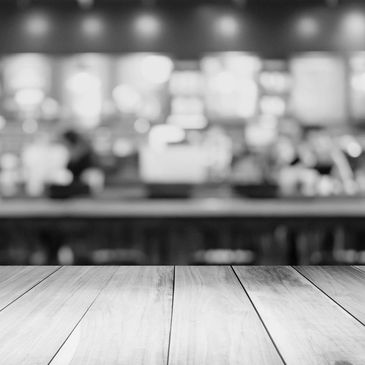 Empty wooden table with blurred cafe background in black and white.