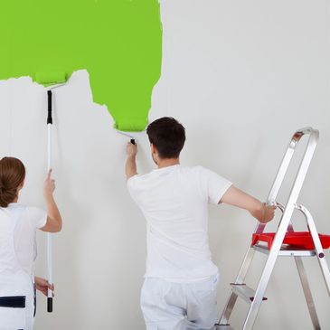 A couple painting a wall green together.
