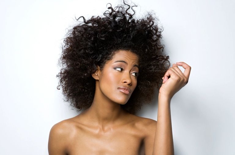African American women looking at hair thinking about how she is going to make her hair and body hap