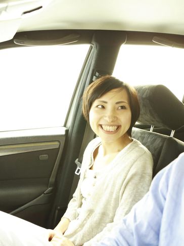 Smiling woman sitting in a car passenger seat, looking at the driver.