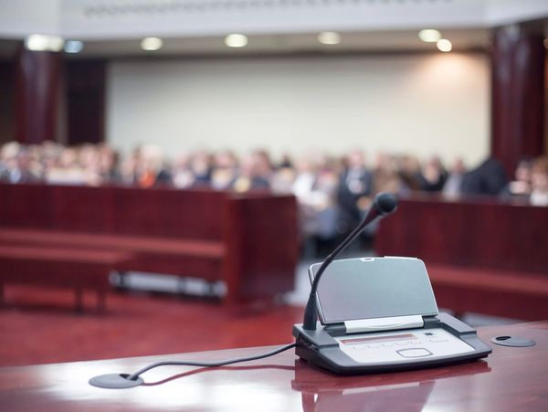 speaker and microphone on a desk in front of a crowded room