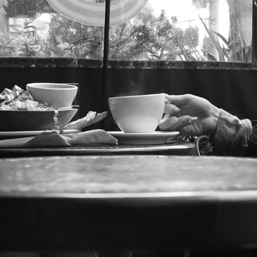 Hand holding a coffee cup at a table with food and drink.