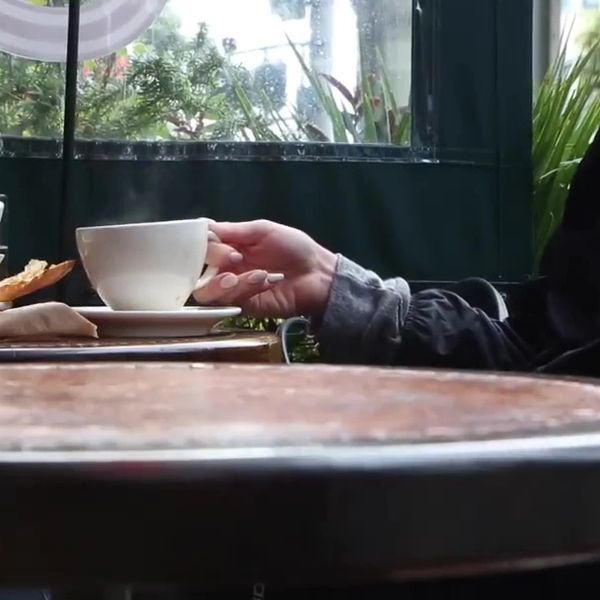 Hand holding a coffee cup in a cozy cafe.